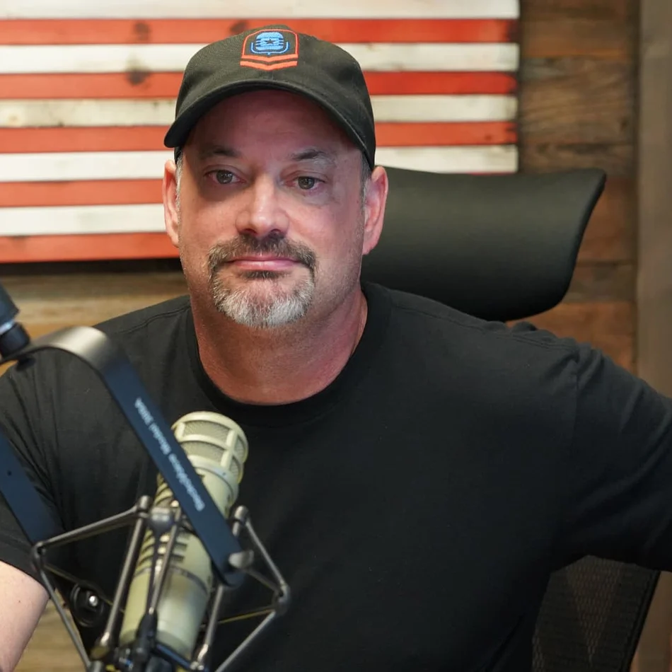 Ed Parcaut at the studio microphone in front of a wooden American flag